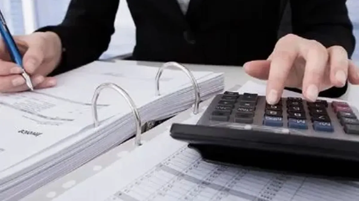 Calculadora y documentos fiscales sobre escritorio con billetes y monedas