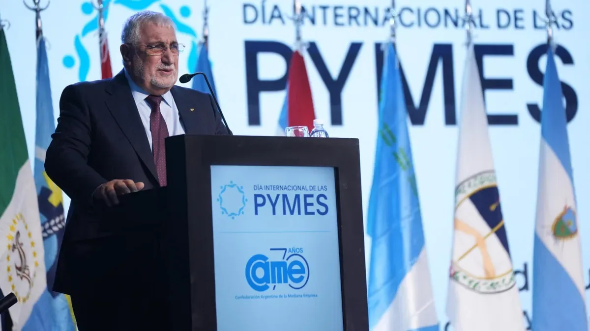 Empresarios pymes reunidos en un evento formal con banderas argentinas y micrófonos en primer plano