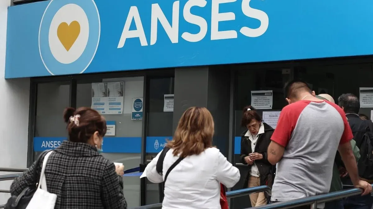 Persona mayor revisando documentos y calculadora en mesa con papeles de ANSES
