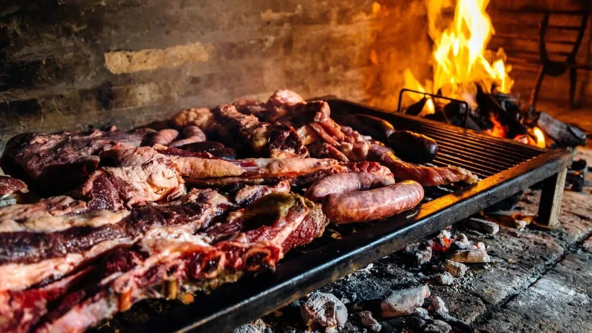 Parrilla con chorizos, morcillas y carne asándose al fuego en un patio argentino