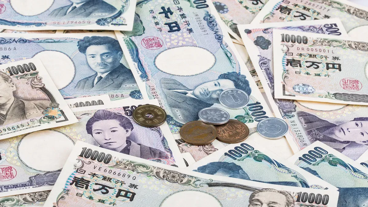 Gráfico del yen japonés cayendo frente al dólar estadounidense con banderas de Japón y EE.UU.