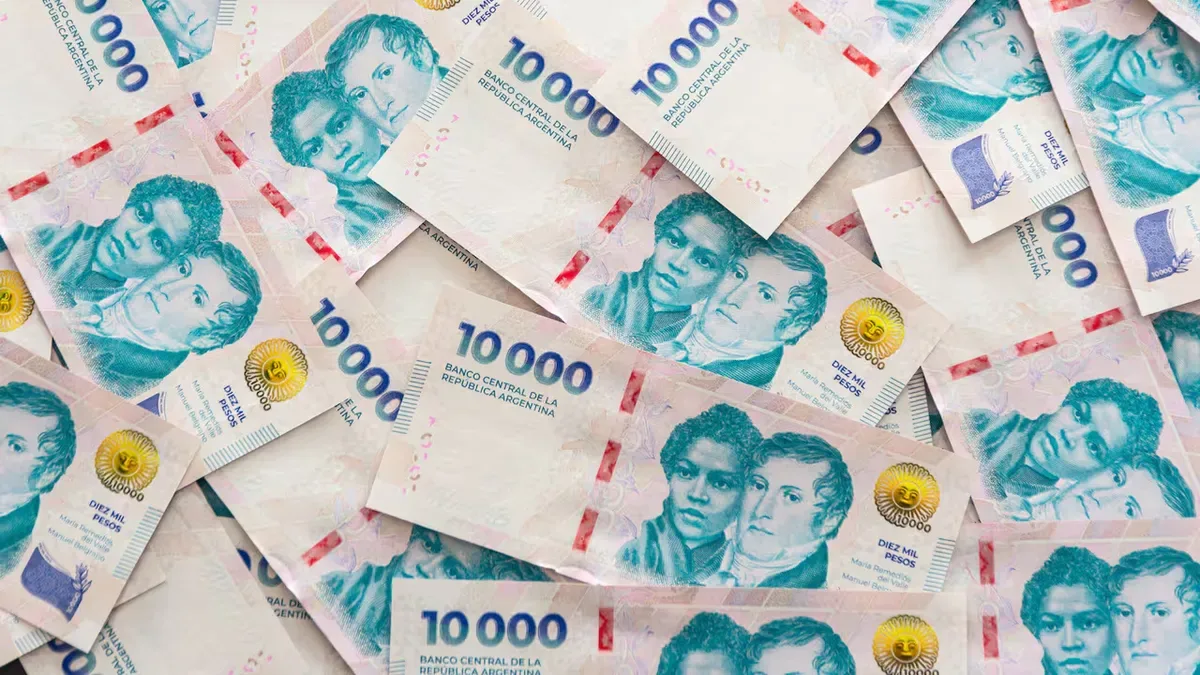 Calculadora financiera con billetes de pesos argentinos y gráfico de interés compuesto