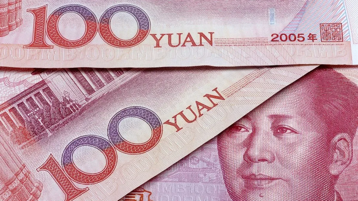 Bandera de China ondeando junto a gráficos financieros y monedas de yuan