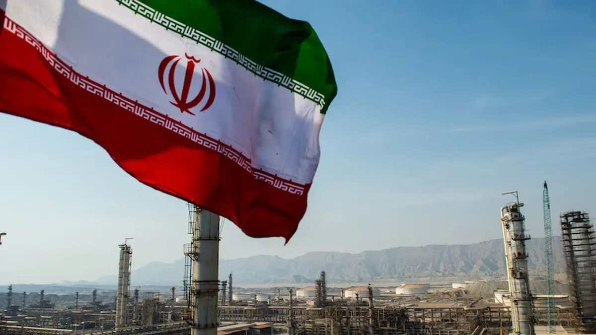 Barco petrolero navegando en el estrecho de Ormuz con banderas de Irán y Estados Unidos al fondo