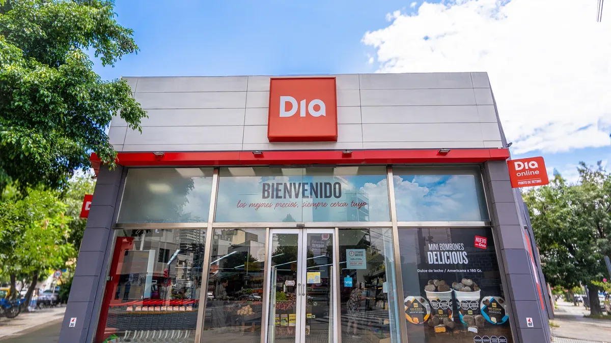 Folletos de ofertas AhorráMás de supermercados Día apilados sobre un carrito de compras en góndola