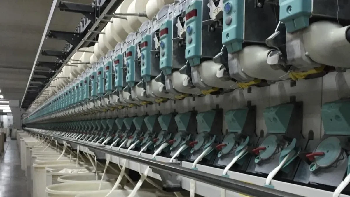 Fábrica textil argentina con máquinas textiles paradas y obreros en la línea de producción