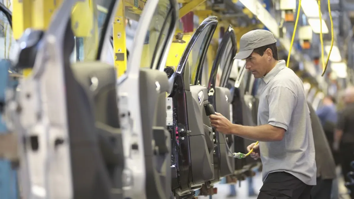Línea de ensamblaje de autos vacía en una planta automotriz argentina con obreros ausentes