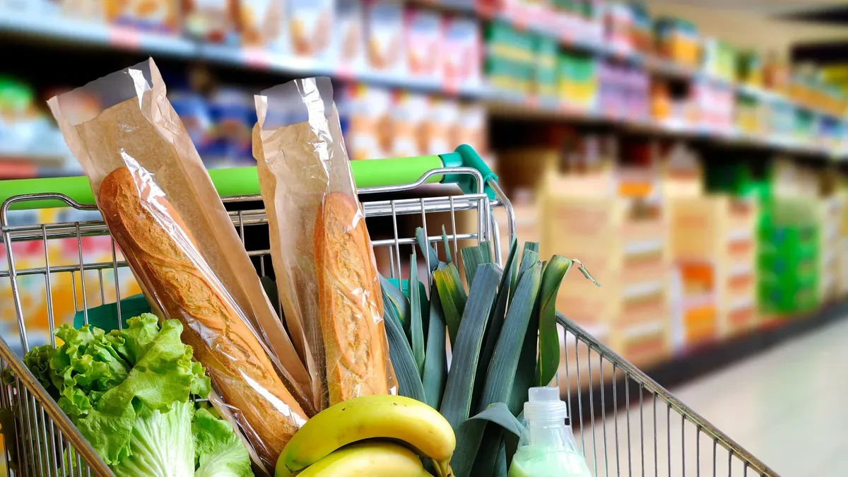 Carrito de supermercado lleno de productos con etiquetas de descuento y cupones en mano