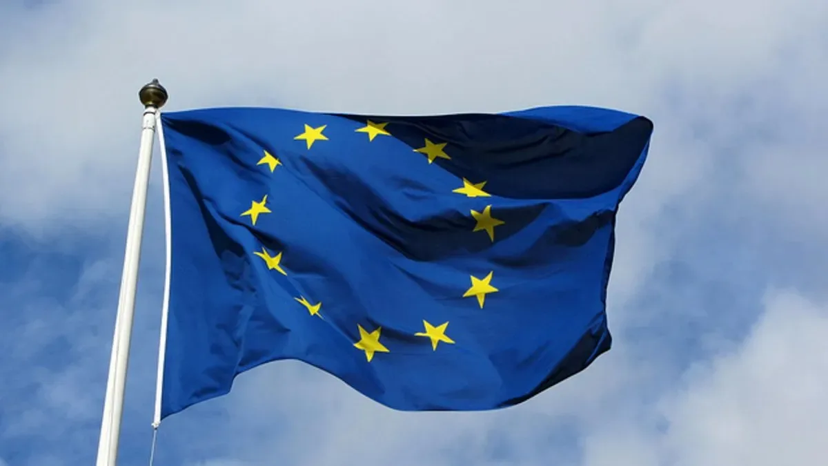 Bandera de la Unión Europea junto a las de Estados Unidos y China en una mesa de negociaciones comerciales