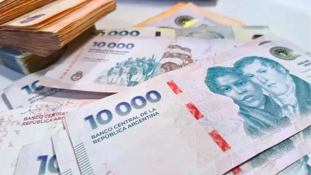 Billetes de pesos argentinos apilados junto a un gráfico de interés compuesto en una tablet
