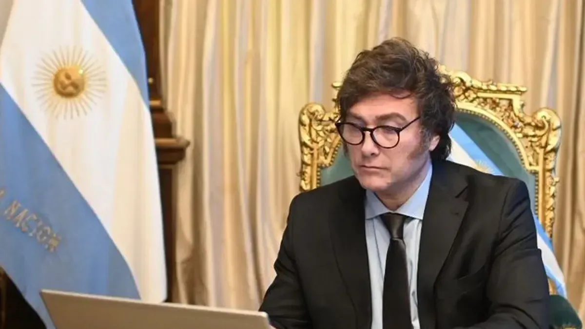 Javier Milei y Demian Reidel en un evento formal, con gráficos económicos de fondo